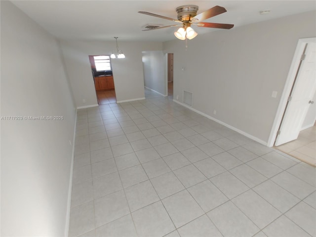 spare room with ceiling fan with notable chandelier and light tile patterned floors