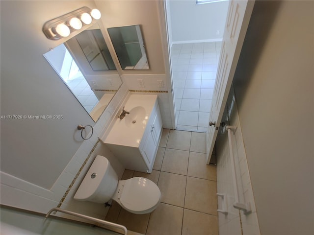 bathroom featuring toilet, vanity, tile patterned floors, and tile walls