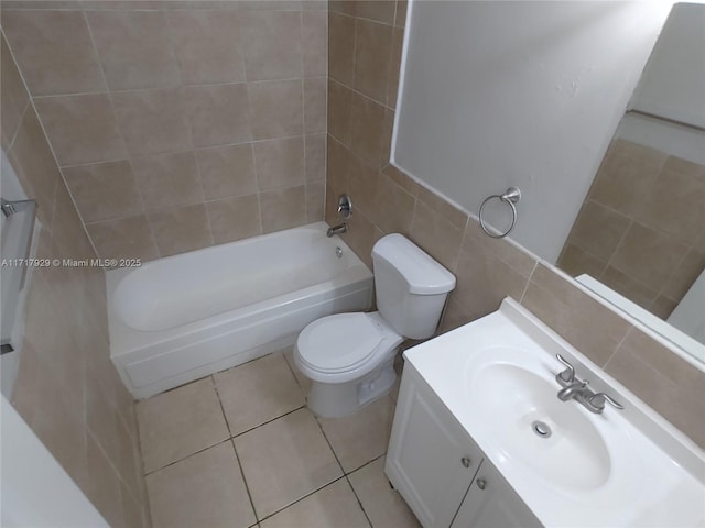 full bathroom featuring vanity, tile patterned floors, tiled shower / bath combo, toilet, and tile walls