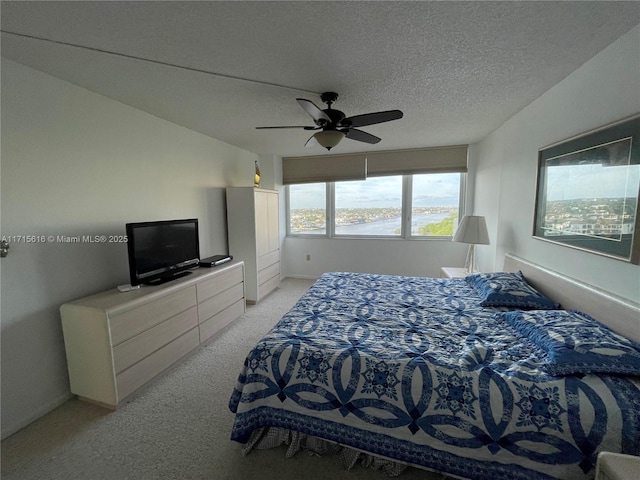 bedroom with a textured ceiling, ceiling fan, and light carpet