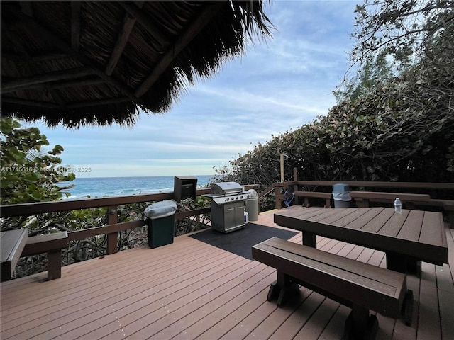 deck with a grill, a water view, and a view of the beach