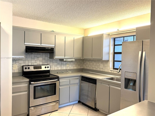 kitchen with appliances with stainless steel finishes, backsplash, extractor fan, sink, and light tile patterned floors