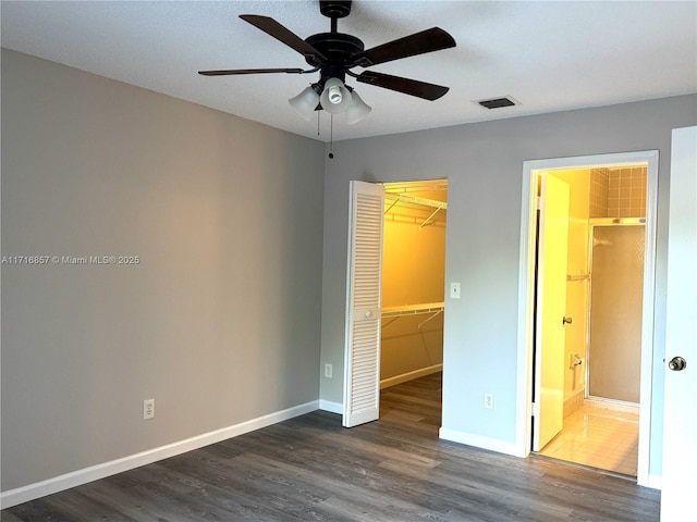 unfurnished bedroom with a walk in closet, ceiling fan, dark hardwood / wood-style floors, connected bathroom, and a closet