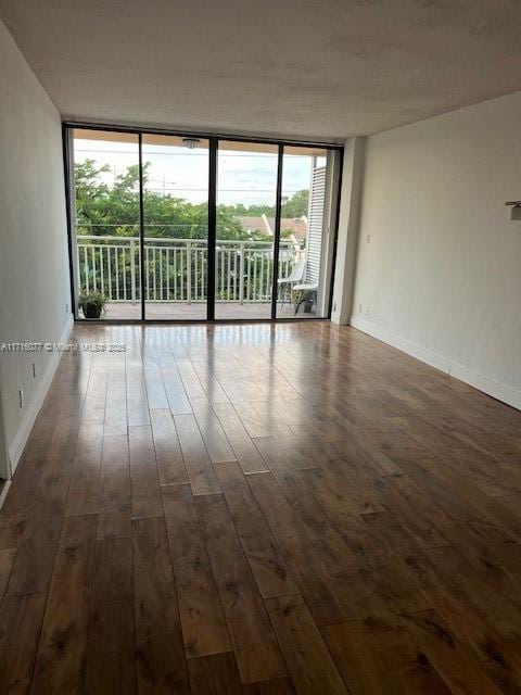 empty room with dark hardwood / wood-style floors and floor to ceiling windows