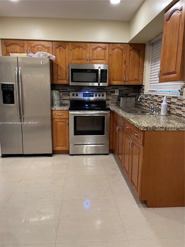 kitchen featuring decorative backsplash, stainless steel appliances, sink, dark stone countertops, and light tile patterned flooring