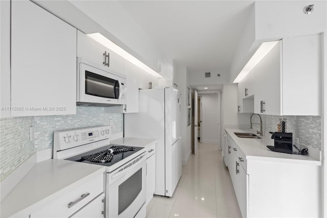 kitchen with decorative backsplash, white appliances, sink, light tile patterned floors, and white cabinetry