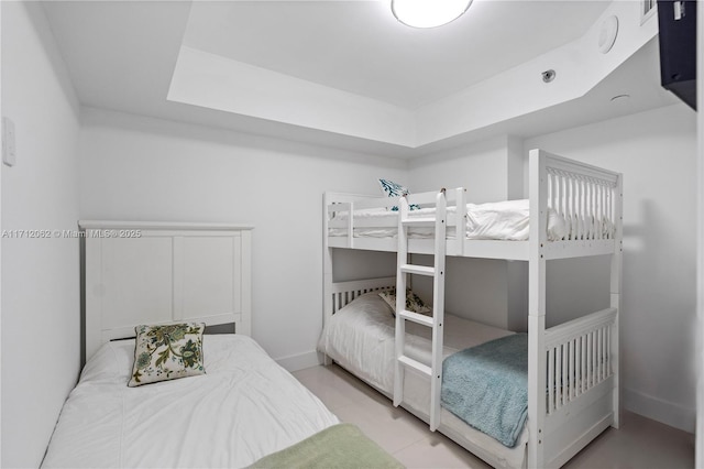 bedroom with light tile patterned flooring and a tray ceiling