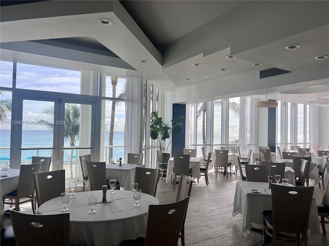 dining room featuring wood-type flooring, a water view, and expansive windows