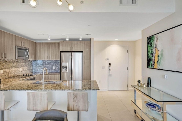 kitchen featuring tasteful backsplash, light stone counters, kitchen peninsula, a breakfast bar area, and appliances with stainless steel finishes