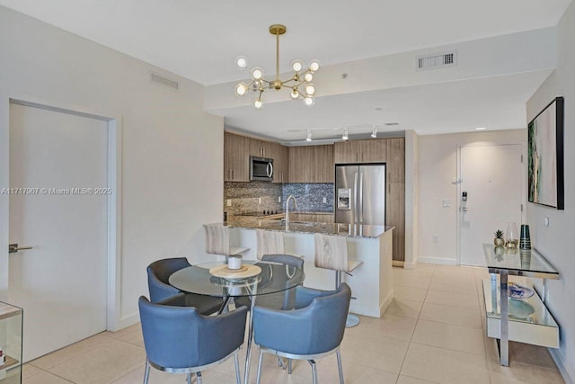 dining room featuring sink, light tile patterned floors, and an inviting chandelier