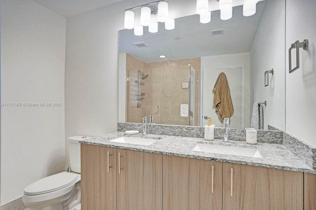 bathroom featuring vanity, a shower with shower door, and toilet