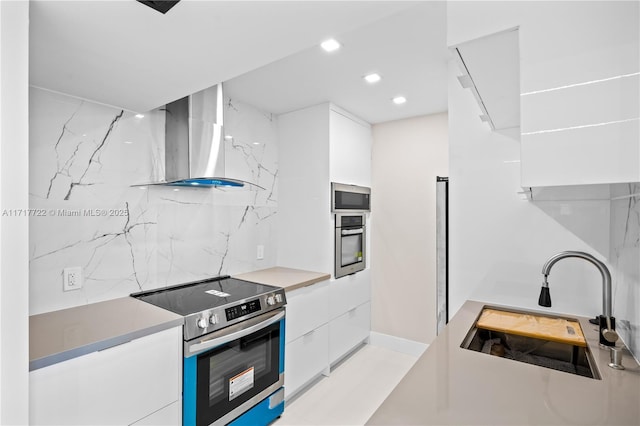 kitchen featuring white cabinets, wall chimney exhaust hood, sink, and appliances with stainless steel finishes