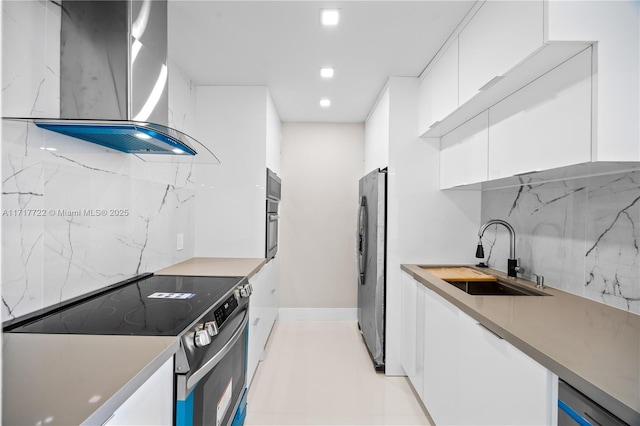 kitchen with decorative backsplash, appliances with stainless steel finishes, wall chimney exhaust hood, sink, and white cabinets