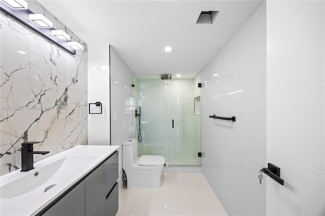 bathroom featuring vanity, toilet, a shower with door, and tile walls