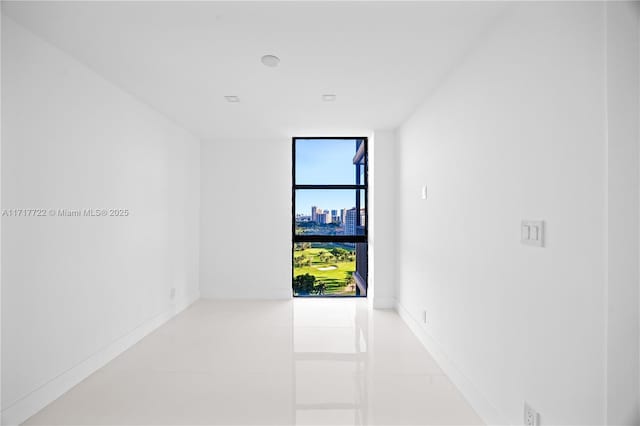 spare room with light tile patterned floors and a wall of windows