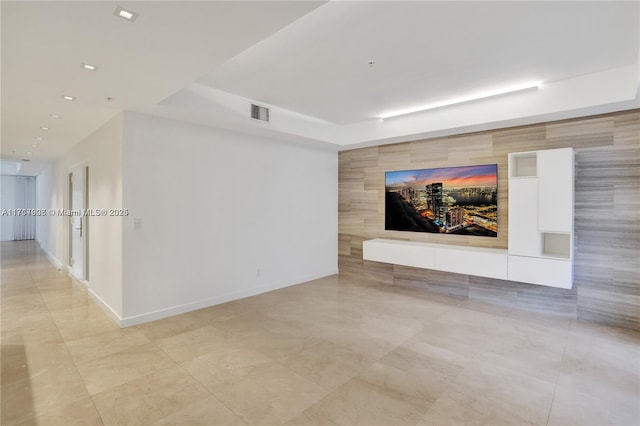 spare room featuring a tray ceiling and tile walls