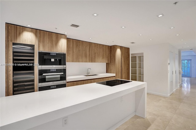 kitchen with black electric stovetop, light tile patterned floors, and sink