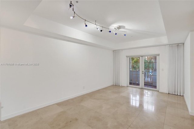 spare room featuring a raised ceiling and french doors