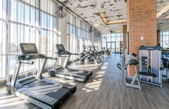 workout area featuring dark wood-type flooring, a towering ceiling, and expansive windows