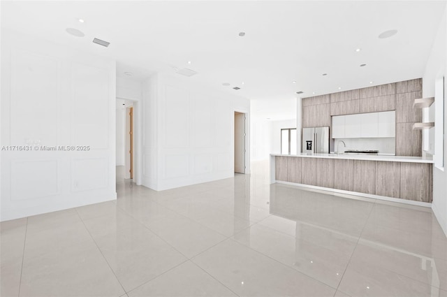 unfurnished living room featuring sink and light tile patterned flooring