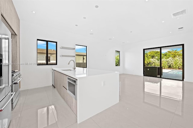 kitchen with dishwasher, sink, wall oven, light brown cabinetry, and light tile patterned flooring