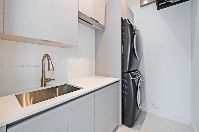 kitchen featuring light tile patterned floors, stacked washer and dryer, and sink