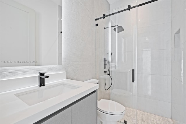 bathroom with a shower with door, vanity, tile walls, and toilet