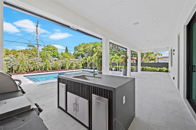 view of patio featuring a fenced in pool, area for grilling, and an outdoor wet bar