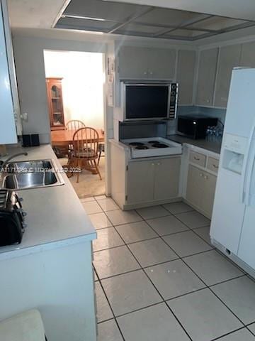 kitchen featuring white cabinets, white fridge with ice dispenser, sink, and light tile patterned floors