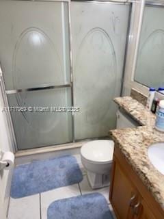 bathroom with tile patterned flooring, vanity, toilet, and walk in shower