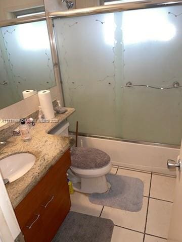 full bathroom with toilet, vanity, tile patterned floors, and enclosed tub / shower combo