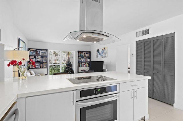 kitchen with white cabinetry, kitchen peninsula, island exhaust hood, oven, and black electric stovetop