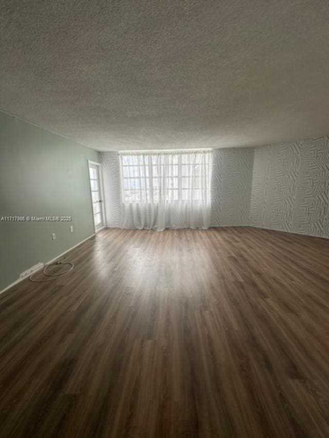 unfurnished room with dark hardwood / wood-style flooring and a textured ceiling