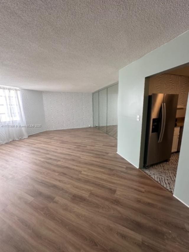 empty room featuring a textured ceiling and dark wood-type flooring