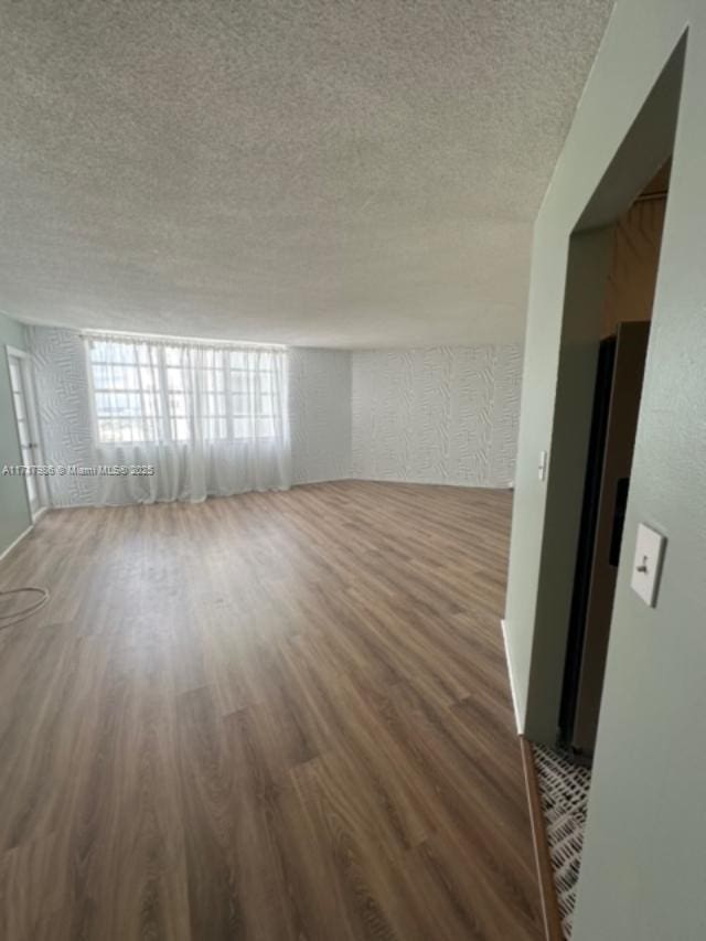 unfurnished room with dark hardwood / wood-style floors and a textured ceiling