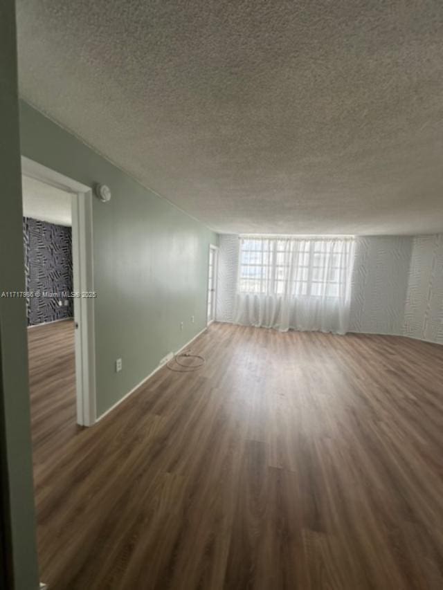 unfurnished room featuring dark hardwood / wood-style flooring and a textured ceiling