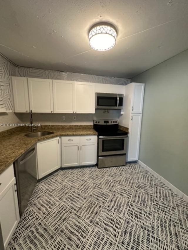 kitchen with stainless steel appliances, white cabinetry, and sink