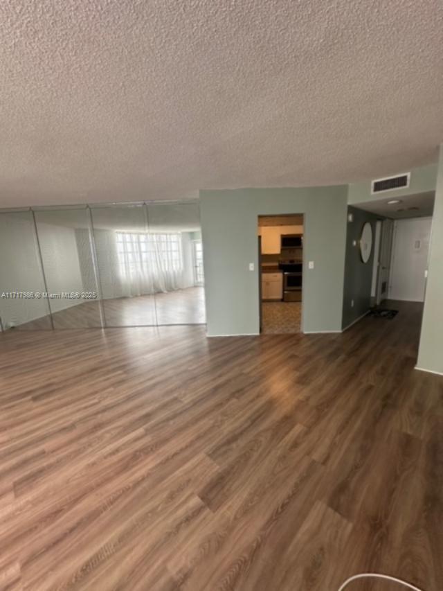 unfurnished living room with wood-type flooring and a textured ceiling