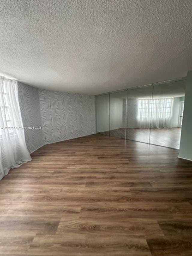 spare room with a textured ceiling, dark hardwood / wood-style flooring, and a wealth of natural light