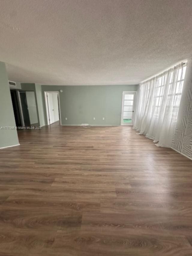 spare room featuring a textured ceiling and dark wood-type flooring