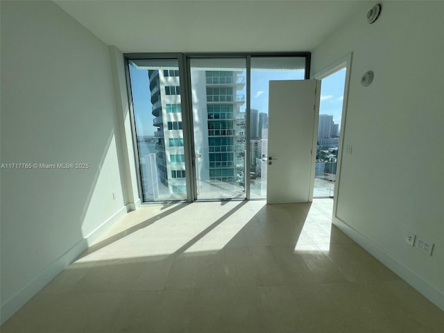 tiled empty room featuring floor to ceiling windows