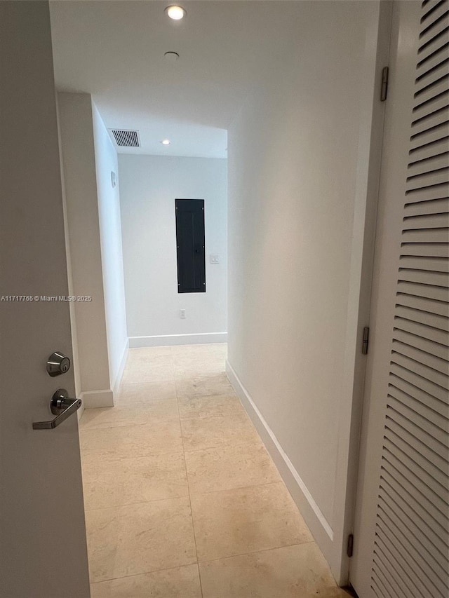 hall with light tile patterned flooring and electric panel