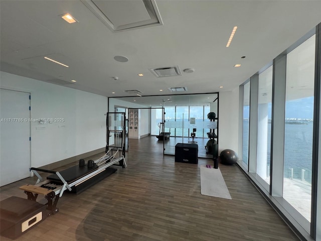 workout area with a water view, floor to ceiling windows, and dark wood-type flooring