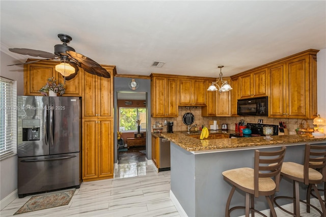 kitchen featuring kitchen peninsula, stainless steel refrigerator with ice dispenser, stove, dark stone counters, and sink