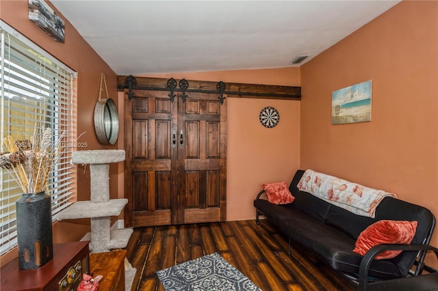 living room with a barn door, dark hardwood / wood-style floors, and vaulted ceiling