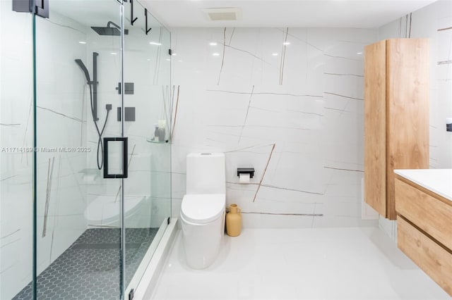 bathroom featuring a shower with door, vanity, tile walls, and toilet