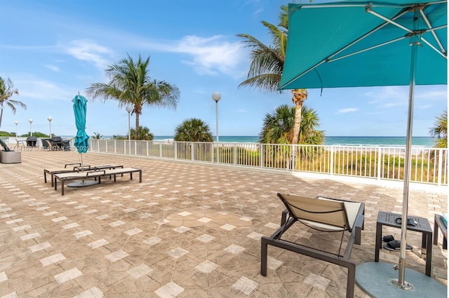 view of property's community featuring a patio area, a beach view, and a water view