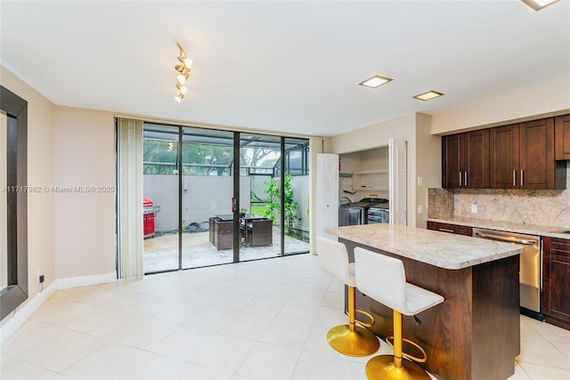 kitchen featuring dishwasher, backsplash, a kitchen bar, washer and clothes dryer, and a kitchen island