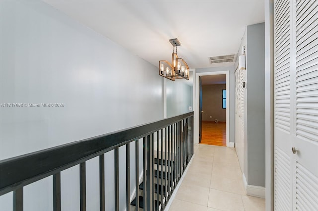 corridor with light tile patterned floors and a notable chandelier