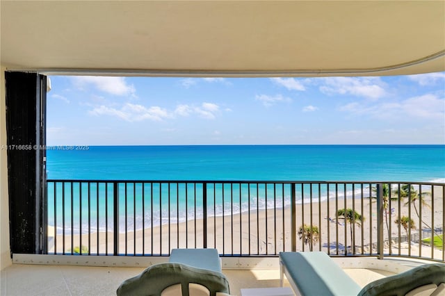 balcony featuring a view of the beach and a water view